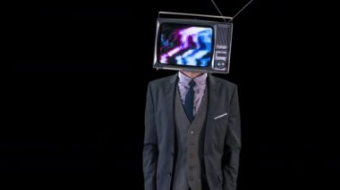 Bay Televizyon Şefi. Takım elbiseli havalı bir adam kafasında televizyonla dans ediyor. Televizyon parazitli ve gürültülü.