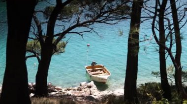 Kristal berraklığında su Adriyatik Denizi, Hırvatistan'ın çarpıcı çam ağaçları ile görülen küçük balıkçı teknesi