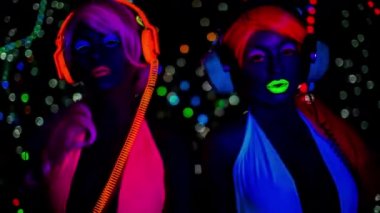 Floresan giyim Uv ışığı altında poz içinde seksi dansçılar.