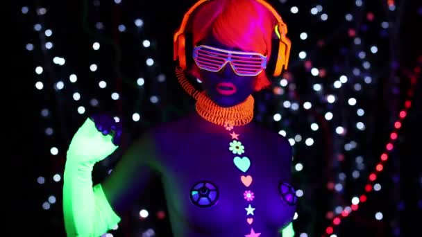荧光眼镜和耳机下的年轻有魅力的女人紫外线黑光 — 图库视频影像