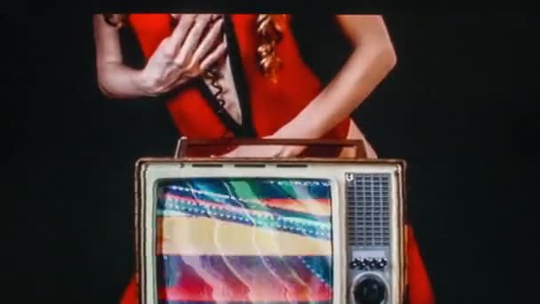 年轻的性感的妇女摆姿势与老式电视在黑色背景 — 图库视频影像