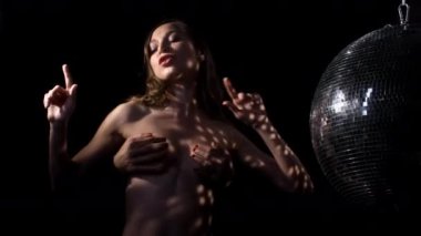 İnsan elleri siyah arka planda disko topuyla çıplak kadın vücuduna dokunuyor.