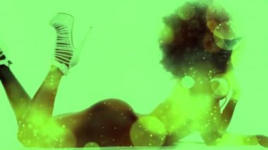 güzel kadın dansçı büyük afro peruk ve kulaklık ile uzanarak. Işık sızıntıları ve yumuşak odak renkli ışıklar ovelayed