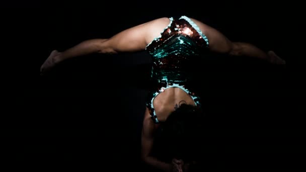 惊人的女性瑜伽教练在闪闪发光的服装之间移动的姿势反对黑色背景 — 图库视频影像