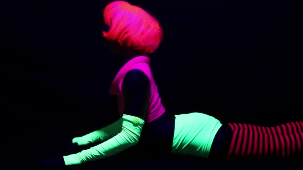 Γυναίκα Στο Φθορισμού Ρούχα Κάνουν Γυμναστικές Ασκήσεις Κάτω Από Μαύρο — Αρχείο Βίντεο