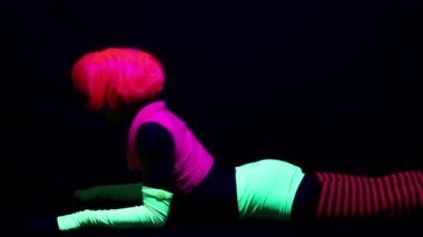 Kadın floresan giyim Uv ultraviyole ışık altında jimnastik egzersizleri yapıyor
