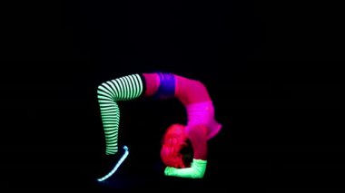 Floresan giyim Uv ultraviyole ışık altında hareketli kadın yoga eğitmeni