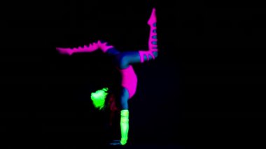 Floresan giyim Uv ultraviyole ışık altında hareketli kadın yoga eğitmeni