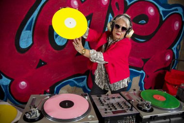 Graffiti duvarının önünde plakla müzik çalan şık bir büyükanne. 
