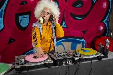 Graffiti duvarının önünde plakla müzik çalan şık bir büyükanne. 