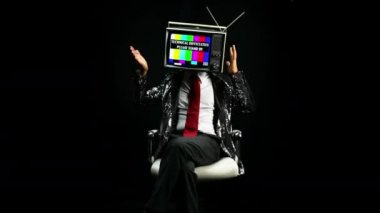 Başında televizyon ile sandalyede oturan adam 