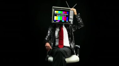 Başında televizyon ile sandalyede oturan adam 