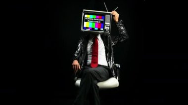 Başında televizyon ile sandalyede oturan adam 