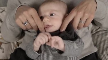 Yeni doğmuş mutlu bir kız bebek anne kucağında dinleniyor. Kadın elleriyle destekleniyor.