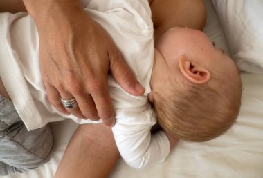 Yatakta annesinin yanında uyuyan güzel bir kız bebek.