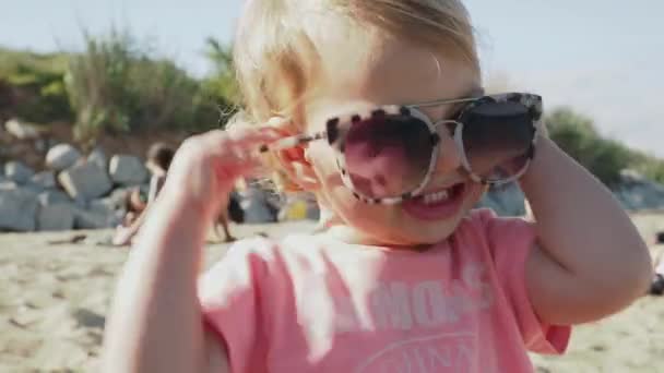 Młoda dziewczyna nosi duże okulary słoneczne na plaży — Wideo stockowe