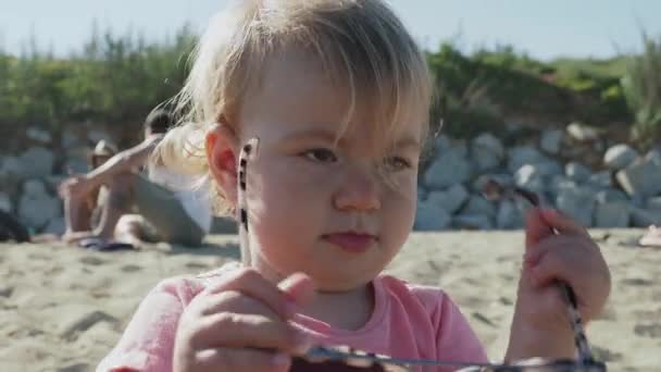 Young girl wearing large sunglasses on beach — Stock Video