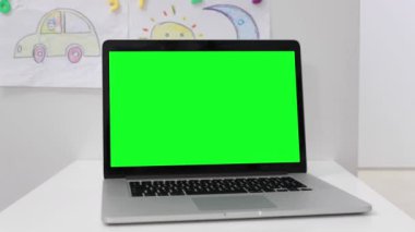 Çocuk odasında yeşil ekranlı bir laptop.