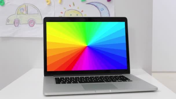 A laptop with a hypnotic rainbow pattern in kids room — Stock Video