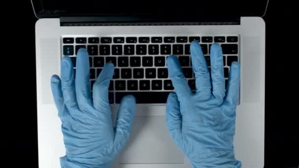 Vídeo de una persona usando guantes de látex usando un ordenador portátil con código de datos en la pantalla — Vídeos de Stock