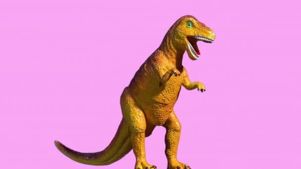 Nagranie plastikowego dinozaura na różowym tle — Wideo stockowe