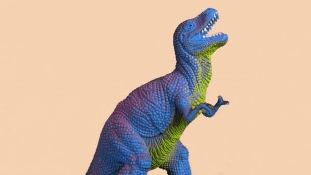 Beelden van plastic dinosaurus tegen oranje achtergrond — Stockvideo