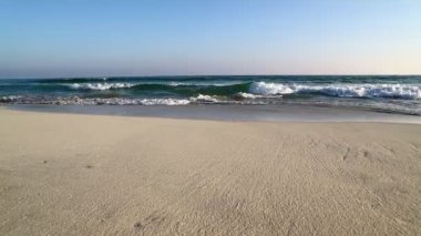 Umman kumsalı ile dalgalı deniz mavi gökyüzü altında görüntüleri