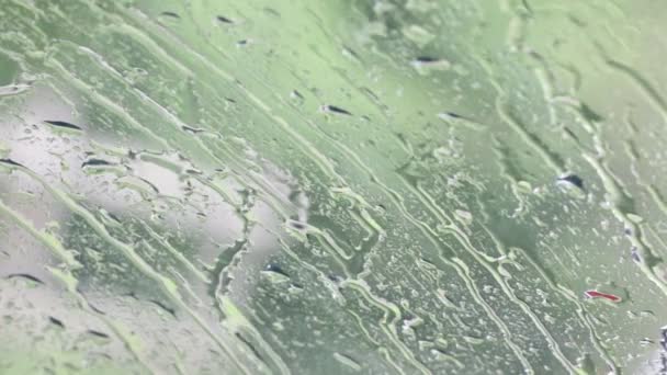 Detailní záběry vodních kapek na okenní sklo s rozmazané pozadí