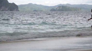 Pasifik Okyanusu'nun Filipinler dalgalar kaya tepeleri yakınlarındaki kumlu plajda rahatlatıcı insanlar, dinlenmek kavramı