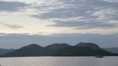 arka planda dağlar ile akşam suda tekne