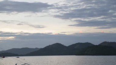 arka planda dağlar ile akşamları su üzerinde tekneler