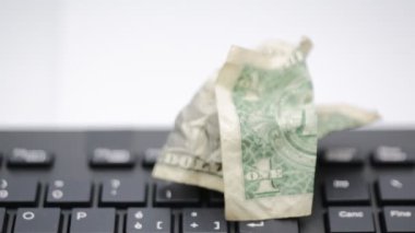 Bilgisayarın klavyesinde duran buruşmuş doların yakın plan görüntüleri.