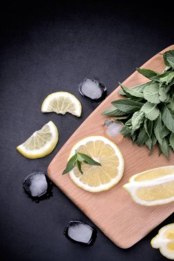 Bir demet taze nane limon dilimleri ve buz küpleri ile ahşap bir tahta üzerinde siyah bir arka plan değil. üstten görünüm.