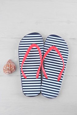 Flip flop kabuk yanındaki mavi ve beyaz bir şerit. Beyaz ahşap arka plan. Yukarıdan görüntüleyin. Plaj aksesuarları.
