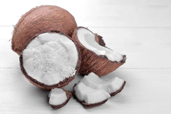 ココナッツ ココナッツ削りと白い木製の背景にココナッツの小さな断片の半分 — ストック写真
