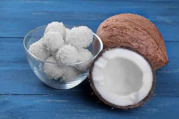 Coconut and half coconut with coconut candies on a blue wooden background