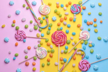 Çok renkli yuvarlak şeker ve parlak renkli arka plan üzerinde renkli lolipop. Üstten görünüm