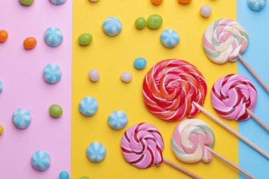 Çok renkli yuvarlak şeker ve parlak renkli arka plan üzerinde renkli lolipop. Üstten görünüm