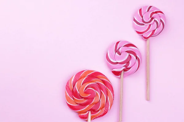 Multicolored lollipops on a stick on a pink bright background. View from above