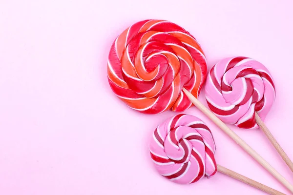 Multicolored lollipops on a stick on a pink bright background. View from above