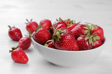 Bir sürü beyaz ahşap zemin üzerinde beyaz bir kase kırmızı çilek