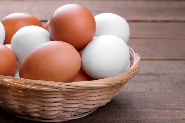 Kahverengi ve beyaz tavuk yumurtası kahverengi ahşap arka plan üzerinde bir hasır sepet içinde.