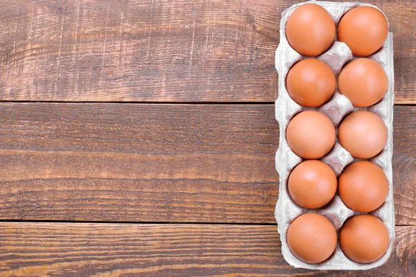 Kahverengi tavuk yumurta yumurta kahverengi ahşap arka plan üzerinde bir tepsi içinde. Üstten görünüm