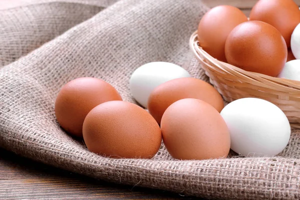 Kahverengi ahşap arka plan üzerinde kahverengi ve beyaz tavuk yumurta yakın çekim.