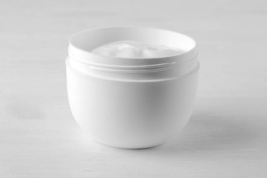 Beyaz ahşap zemin üzerinde beyaz kavanozda yüz kremi