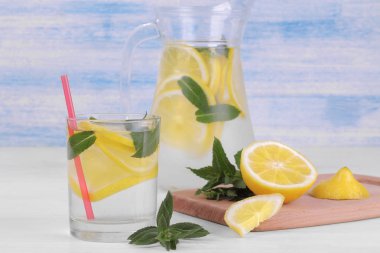 Ev yapımı limonata limon ve nane bir cam sürahi ve bardak taze limon beyaz ve mavi ahşap arka plan üzerinde yanında