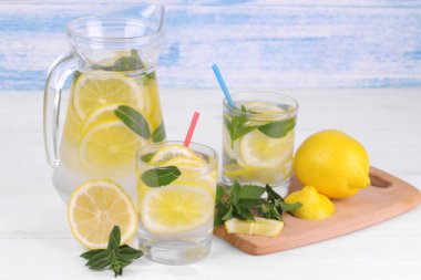 Ev yapımı limonata limon ve nane bir cam sürahi ve bardak taze limon beyaz ve mavi ahşap arka plan üzerinde yanında