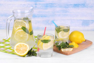 Ev yapımı limonata limon ve nane bir cam sürahi ve bardak taze limon beyaz ve mavi ahşap arka plan üzerinde yanında