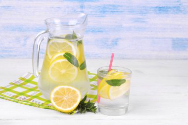 Ev yapımı limonata limon ve nane bir cam sürahi ve bardak taze limon beyaz ve mavi ahşap arka plan üzerinde yanında