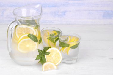 Ev yapımı limonata limon ve nane bir cam sürahi ve bardak taze limon beyaz ve mavi ahşap arka plan üzerinde yanında...